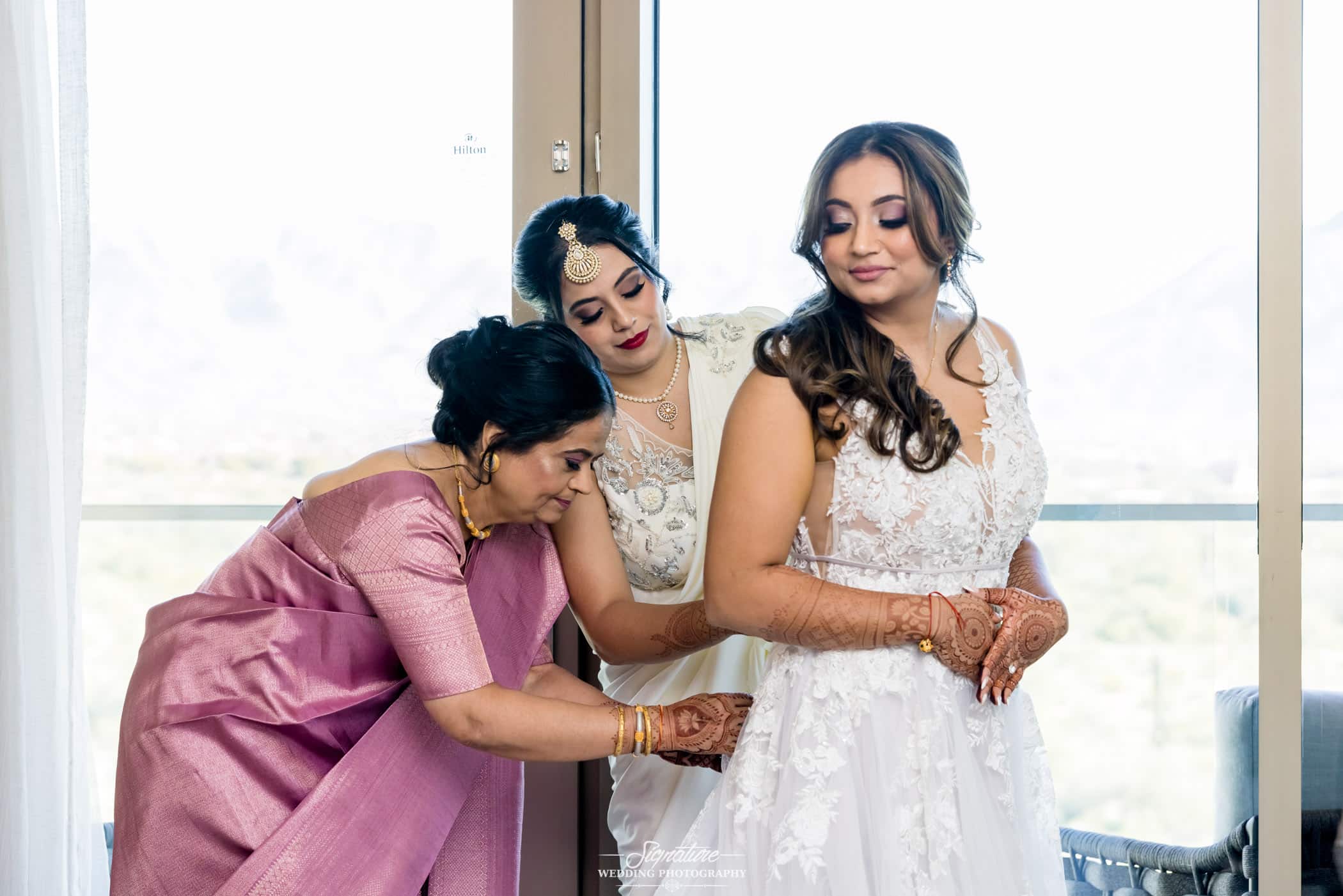 Bridesmaids helping bride with dress