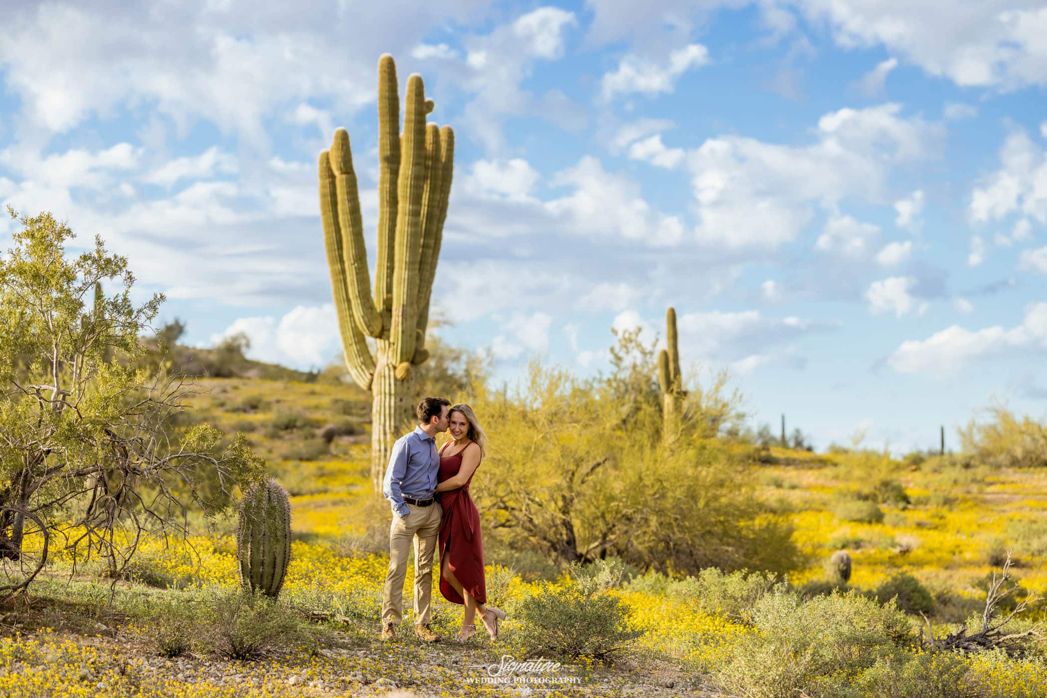 Man kissing woman's cheek in front of cactus