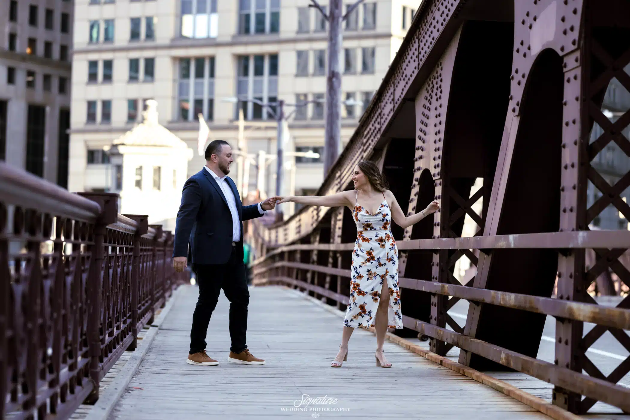 Image by Signature Wedding Photography engagement photo of couple dancing on a bridge in chicago
