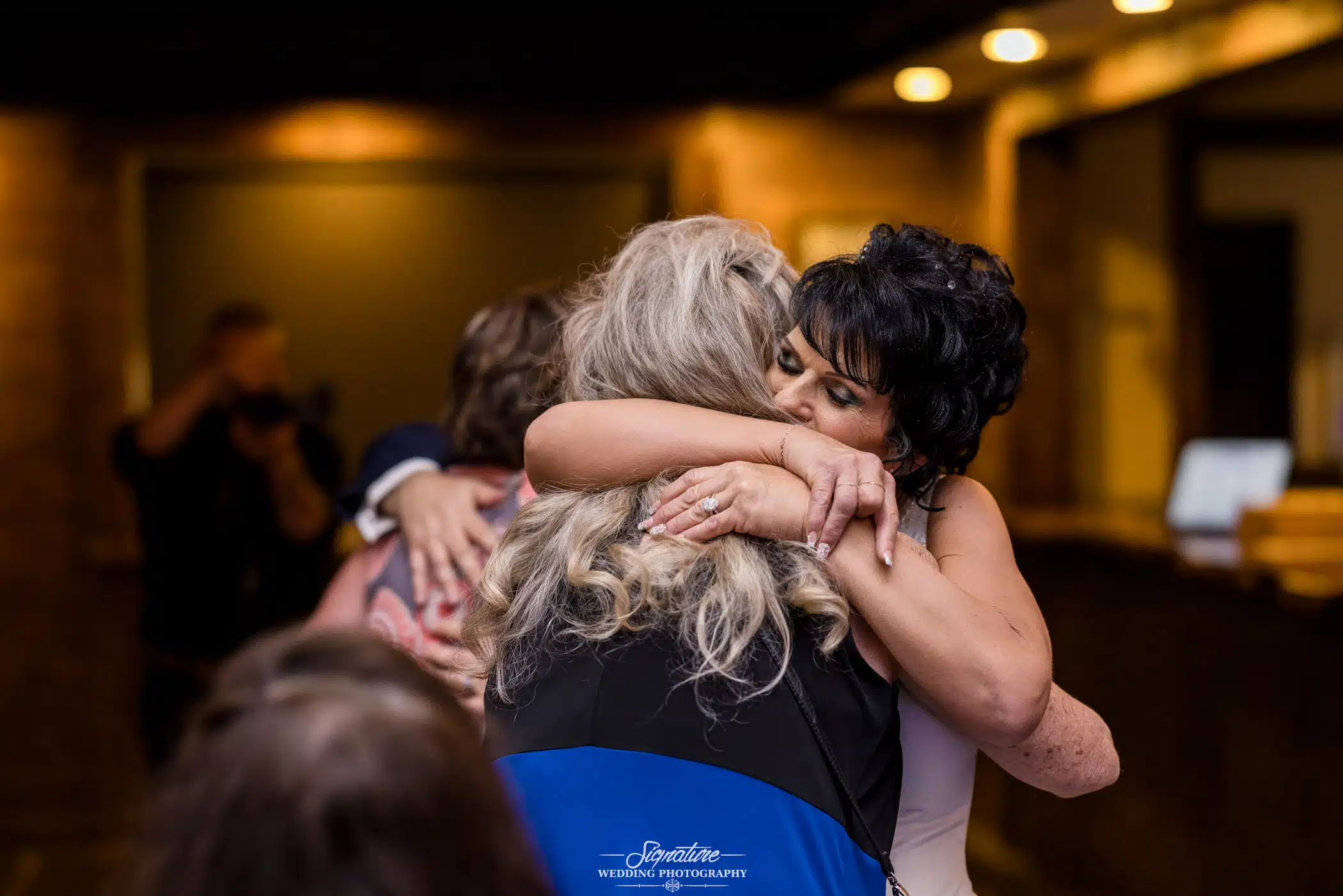 Image by Signature Wedding Photography bride hugging her friend intensely