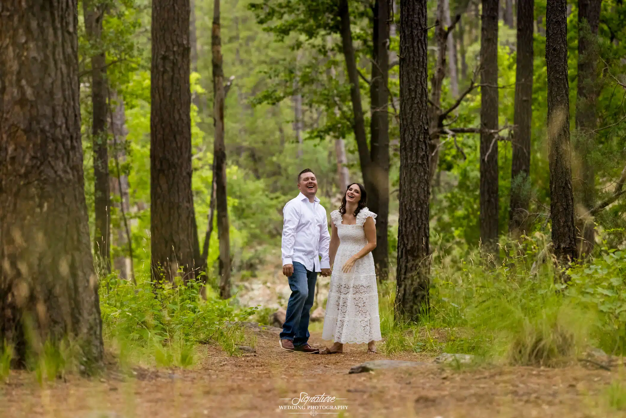 Image by Signature Wedding Photography candid moment during an engagement photo session in the woods