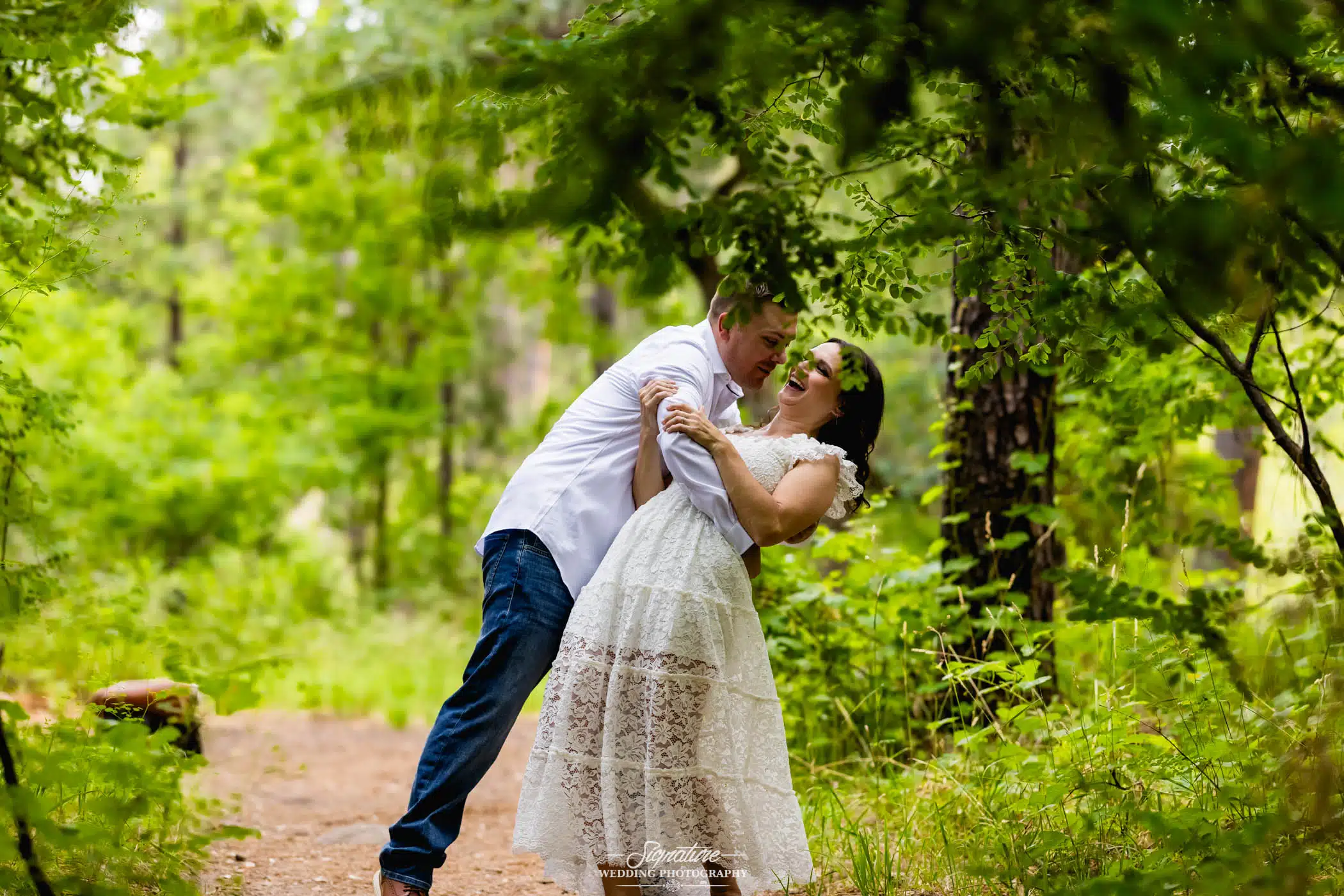 Image by Signature Wedding Photography fun photo of man dipping his fiancée in the woods