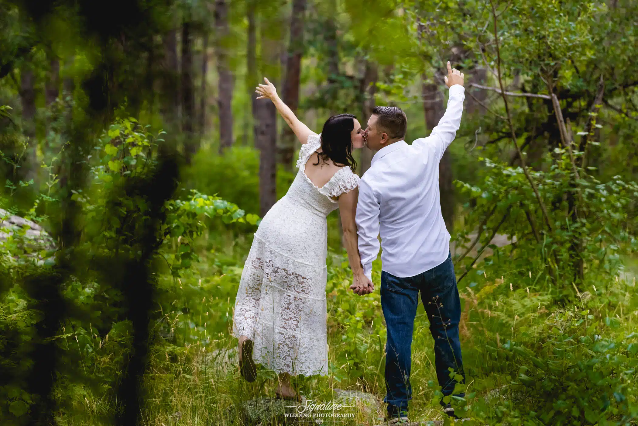 Image by Signature Wedding Photography couple holding hand while kissing in the woods