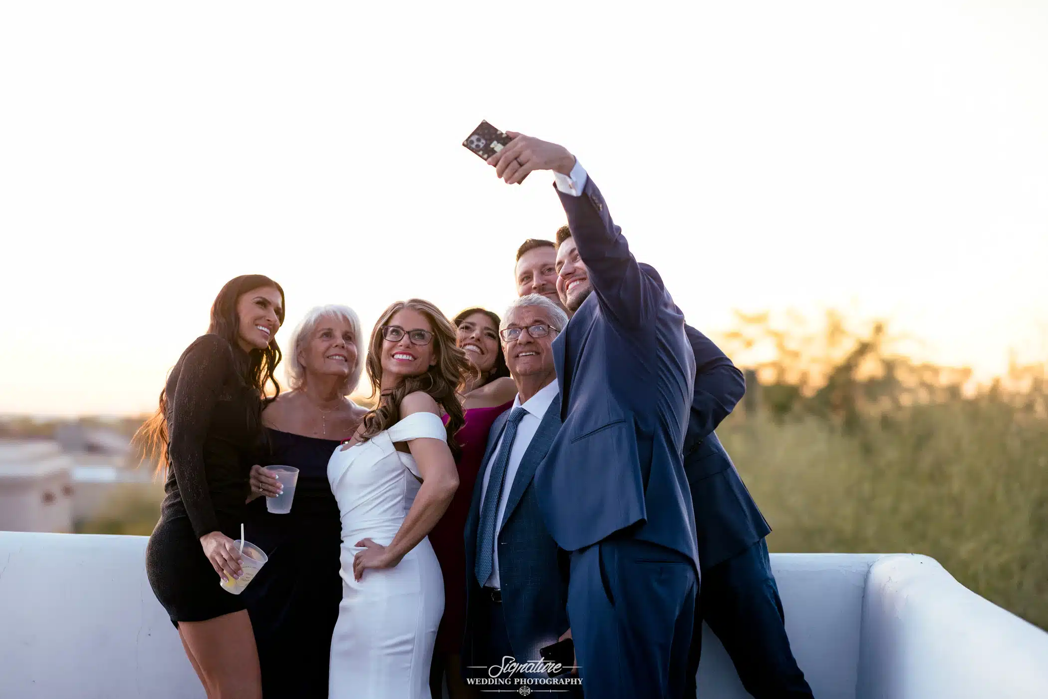 Image by Signature Wedding Photography man taking selfing of wedding party
