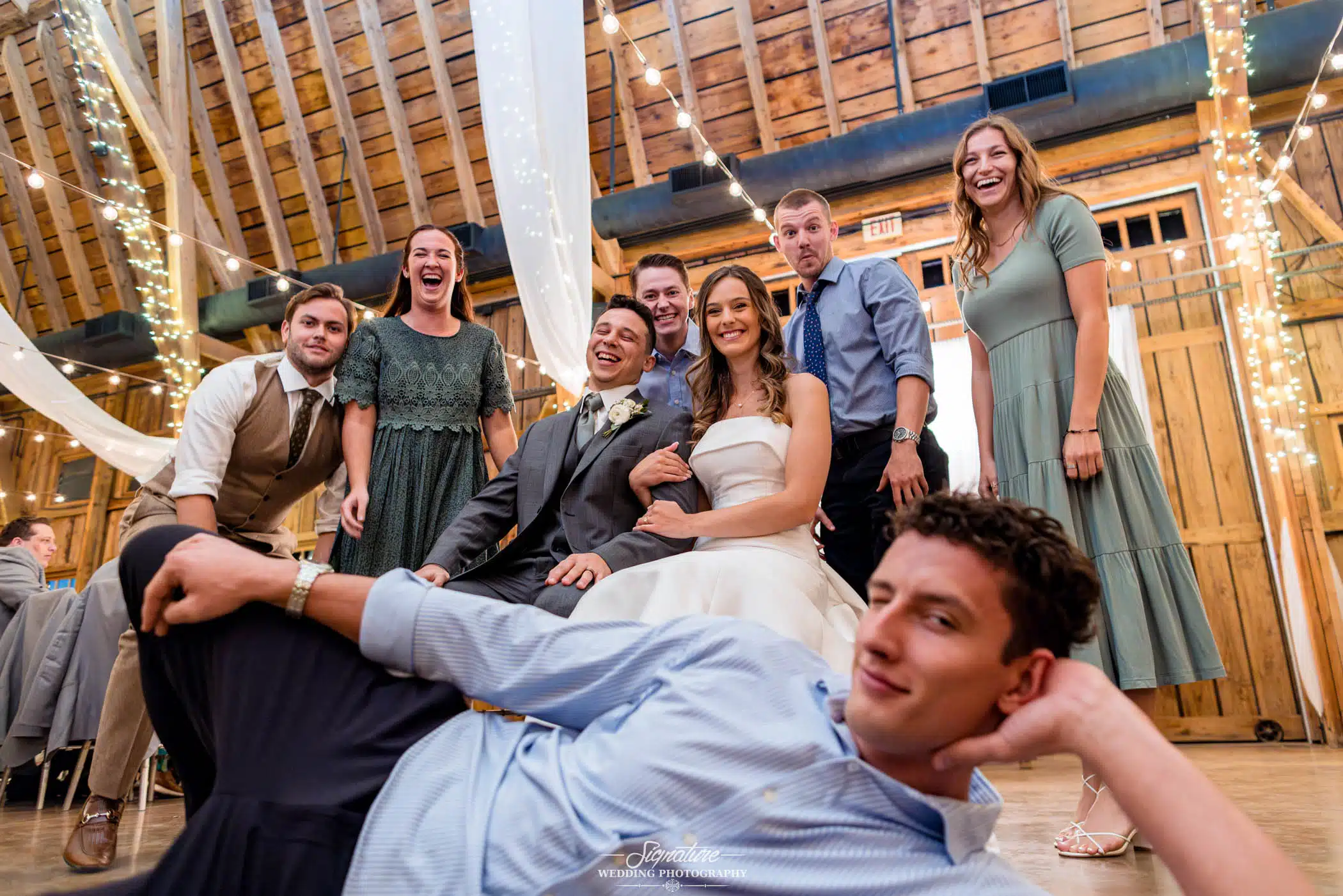 Image by Signature Wedding Photography candid group photo of bride and groom with family & friends