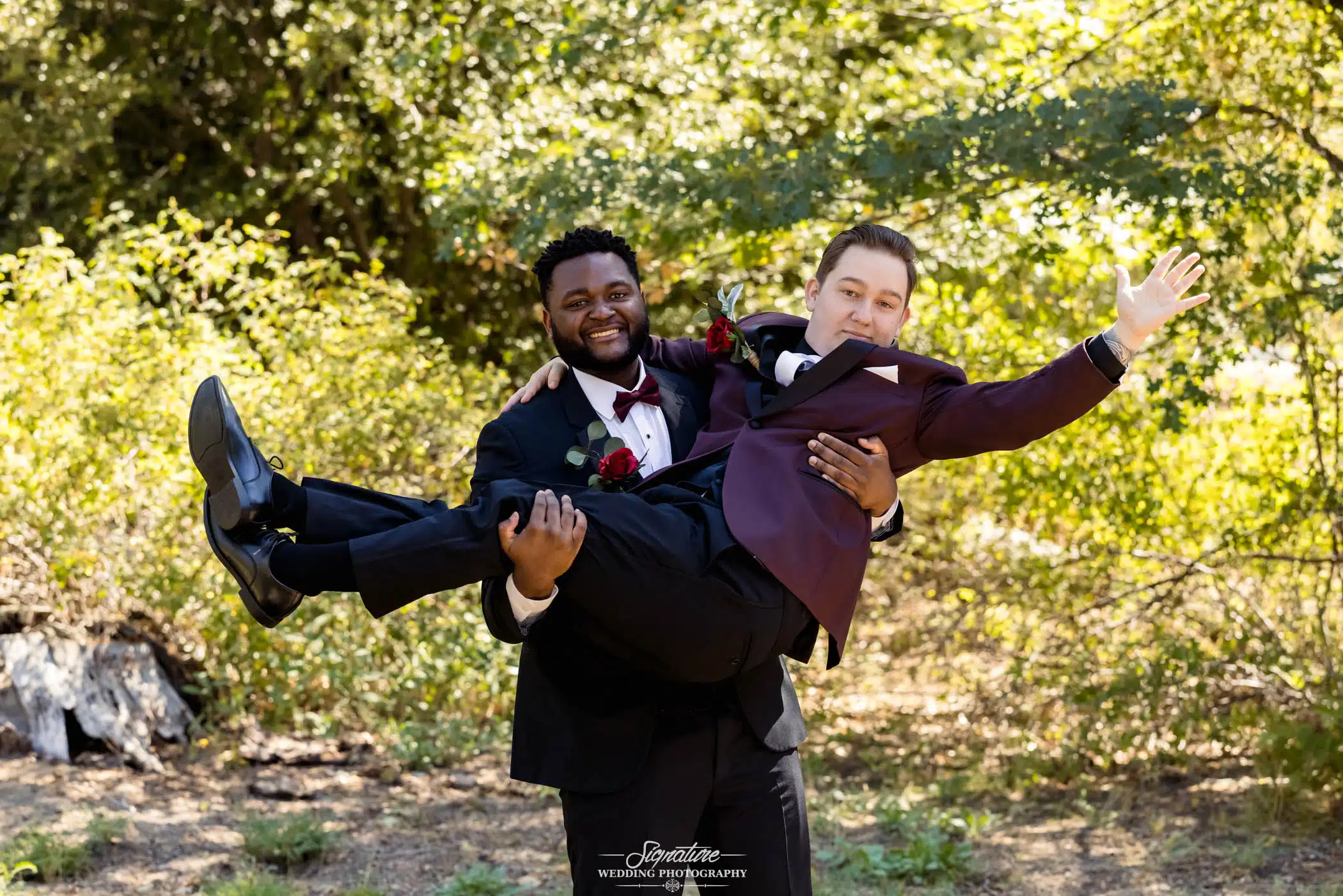 Image by Signature Wedding Photography groomsman carrying groom with sunlit woods in the background
