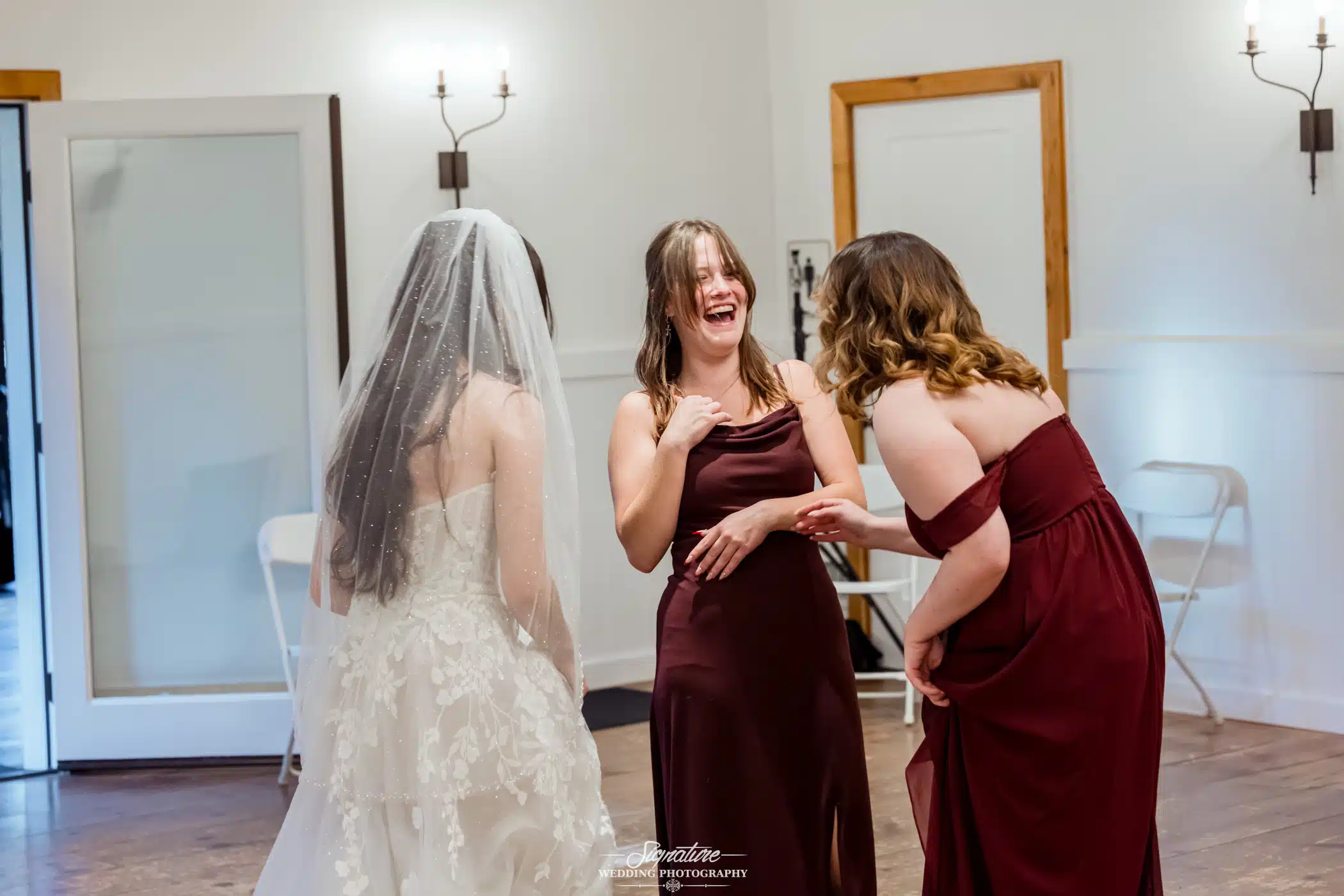 Image by Signature Wedding Photography candid photo of bride and a couple bridesmaids laughing