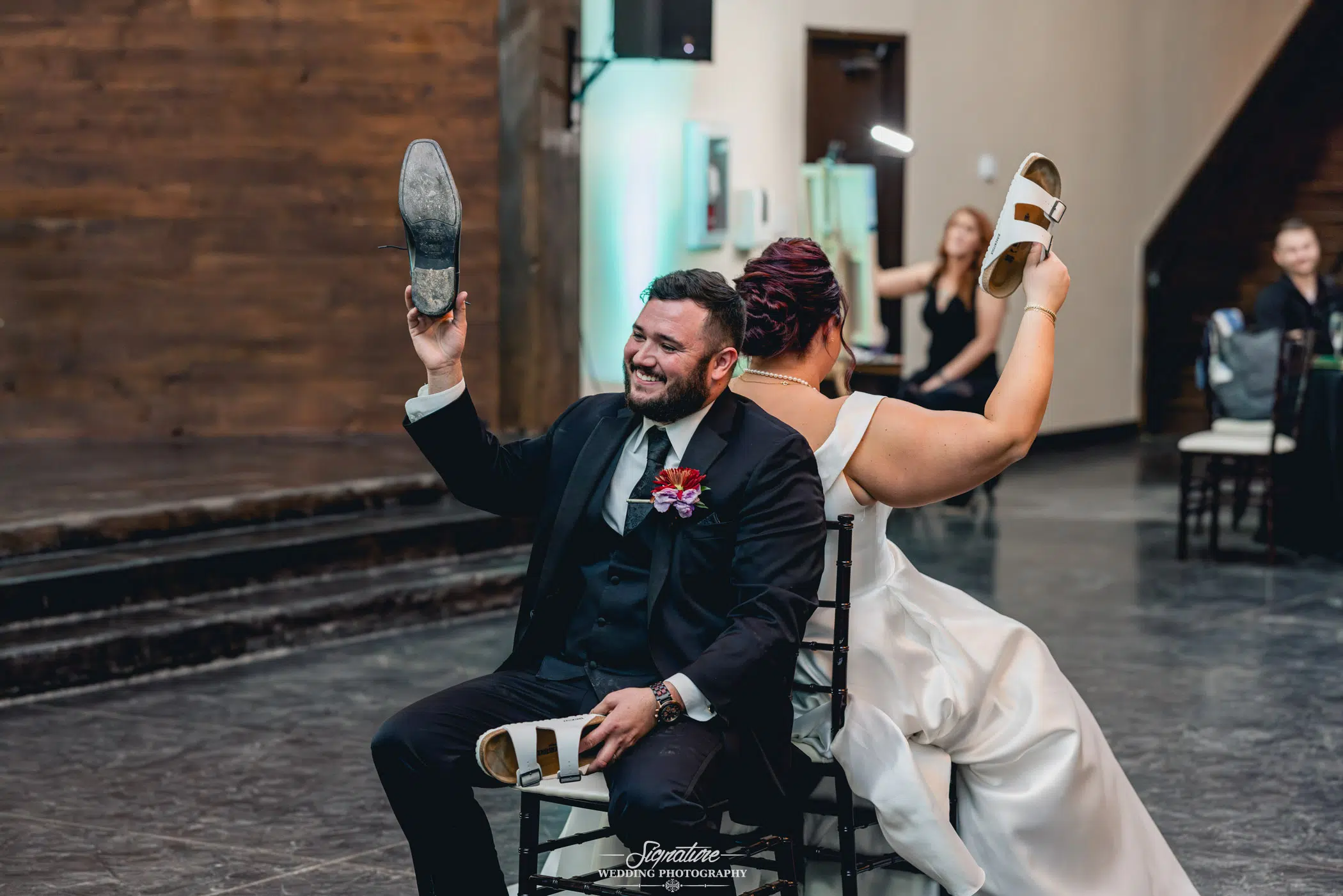 newleyweds holding up one of their shoes in a wedding tradition