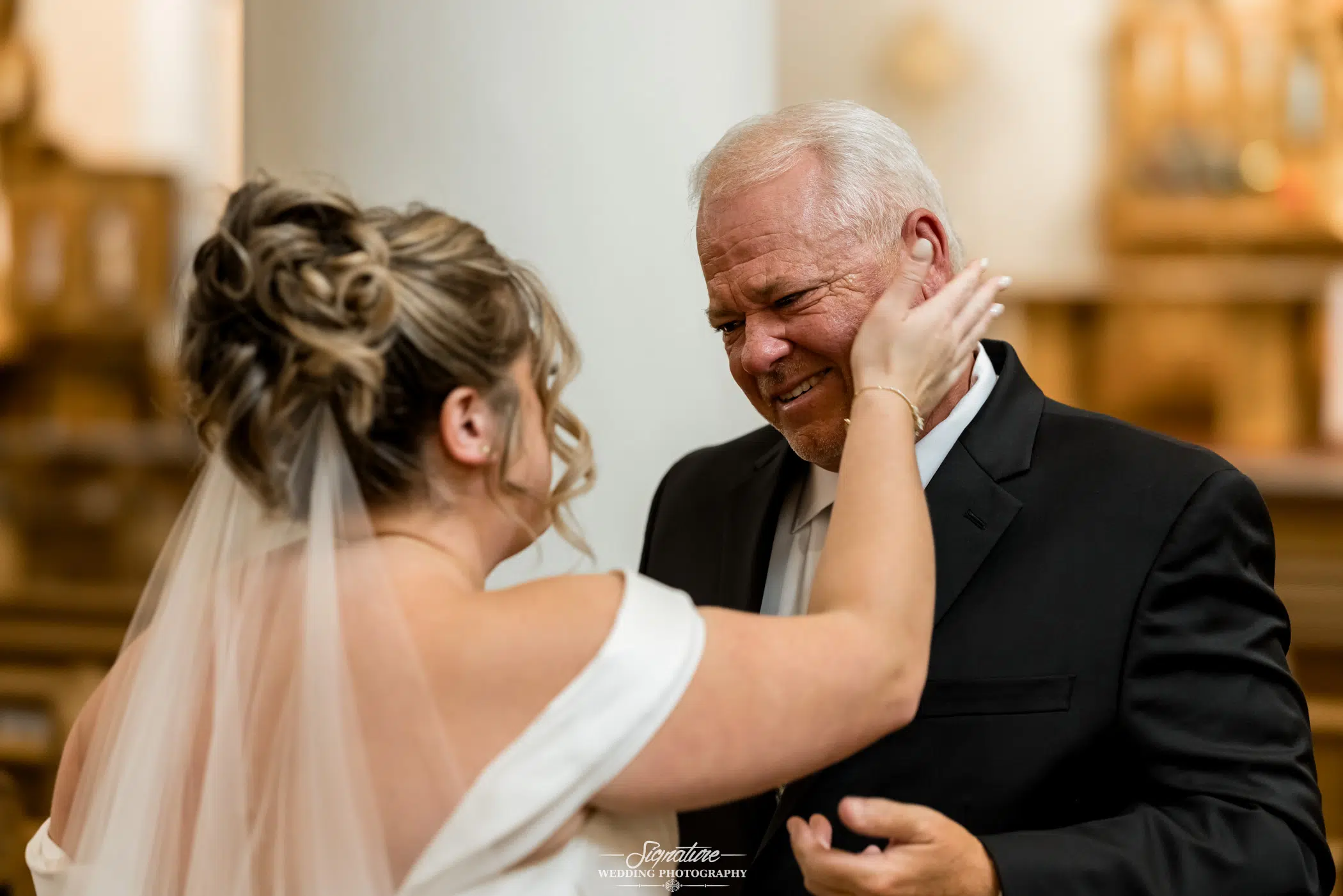 A bride-to-be puts her hand on her dad's face after he brings her up to the alter to wed