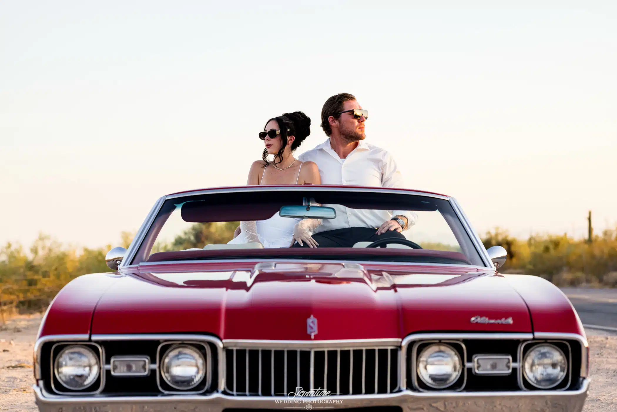 couple sitting in a vintage car looking opposites directions.